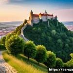 브르노의 역사적 명소 - A majestic medieval fortress perched on a hilltop overlooking a European city at sunset, featuring t...
